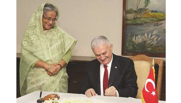 Prime Minister Sheikh Hasina looks on as Turkish Prime Minister Binali Yildirim signs the visitorsu2019 book at PM Office in Dhaka yesterday.