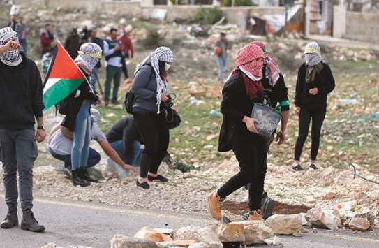 Palestinian protesters build a barricade during clashes with Israeli security forces at Atarot checkpoint on the northern outskirts of Jerusalem, yesterday.
