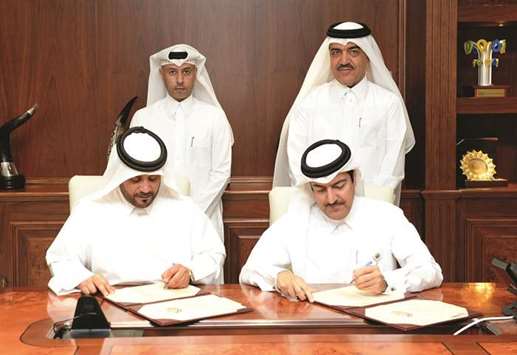 HE the Minister of Administrative Development, Labour and Social Affairs Dr Issa  Saad al-Jafali al-Nuaimi and HE the Minister of Municipality and Environment Mohamed bin Abdullah al-Rumaihi look on as the MMEu2019s Mohamed Ali al-Khuri and Barwau2019s Salman Mohamed al-Mohannadi sign the contract.