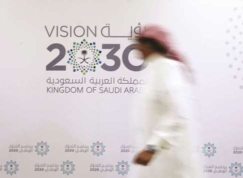 A Saudi man walks past the logo of the Vision 2030 in Jeddah (file). Almost seven weeks after the purge started, authorities are detaining new suspects and releasing some of those held, according to people familiar with the situation.
