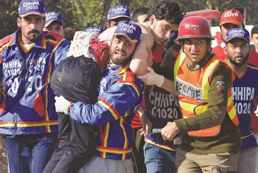 Volunteers carry an injured student from the Agriculture Training Institute in Peshawar after the attack by Taliban militants.