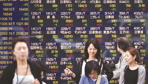 Pedestrians walk past an electronic quotation board in Tokyo. The Nikkei 225 closed up 0.4% to 22,819.03 points yesterday.