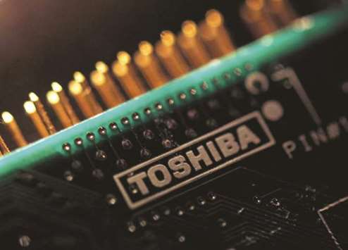 A Western Digital Corporation hard drive is pictured here in Encinitas, California. Right: A logo of Toshiba is seen on a printed circuit board in Tokyo. Western Digital plans to end arbitration claims in the US to stop Toshiba from selling the chip  business to a consortium led by Bain Capital as part of the settlement, said people familiar with the matter.
