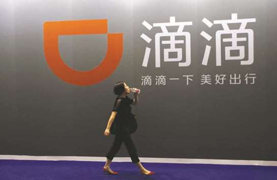 A woman walks past ride-hailing company Didi Chuxingu2019s booth at the Global Mobile Internet Conference (GMIC) 2017 in Beijing. Didi is already one of Chinau2019s most richly funded private companies and its backers range from the countryu2019s sovereign wealth fund to e-commerce giant Alibaba, WeChat-operator Tencent Holdings and Apple.