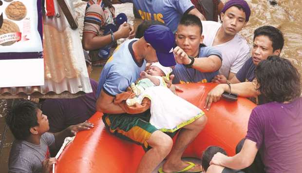 Policemen evacuate a baby in Cagayan City yesterday, after the Cagayan River swelled caused by heavy rains brought by tropical storm Tembin.