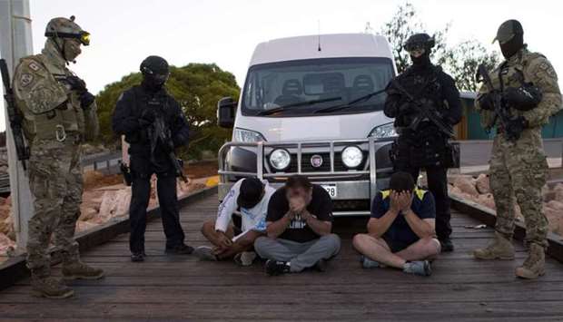 Australian Federal Police SWAT officers watching over suspects after 1.2 tonnes of methamphetamine commonly known as ,ice, was intercepted being offloaded ffrom a boat