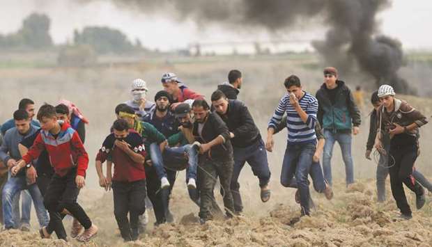 Palestinian protesters carry a wounded comrade during clashes with Israeli soldiers near the border fence, east of Gaza City, yesterday.