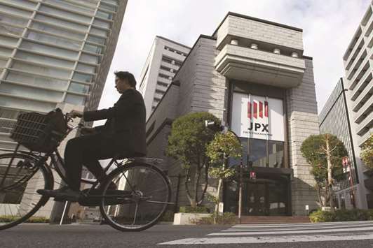 A man cycles past the Tokyo Stock Exchange. Japanu2019s benchmark Topix index has rallied 20% this year as global growth has helped generate record Japanese corporate profits.