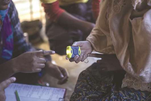 A Rohingya woman is instructed on how to use an alarm device issued by Moonlight Development Society at a clinic in the Chakmarkul refugee camp in Coxu2019s Bazar.
