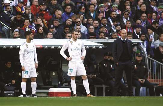 Real Madridu2019s coach Zinedine Zidane (right) looks on as midfielder Marco Asensio (left) and forward Gareth Bale wait to come as substitute against Barcelona in Madrid. (AFP)