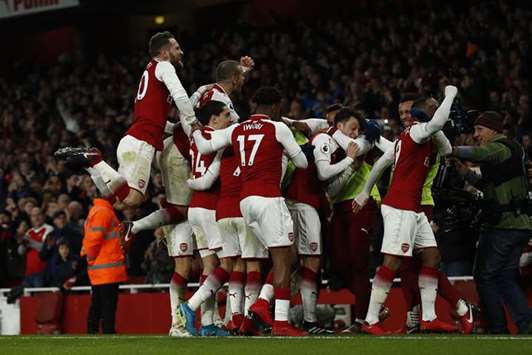 Arsenalu2019s Mesut Ozil celebrates after scoring the teamu2019s third goal with teammates during the English Premier League match against Liverpool in London on Friday night. (AFP)