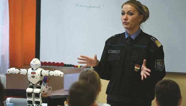 Schoolchildren listen to a presentation about the Internet security given by local police chief Lieutenant-Colonel Zita Szabo with her helper Robi in the classroom of a primary school in Szolnok, about 100km east of Budapest.