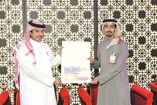 Ahmed al-Henzab accepted a trophy and a plaque of appreciation from Hassan al-Ajmi.