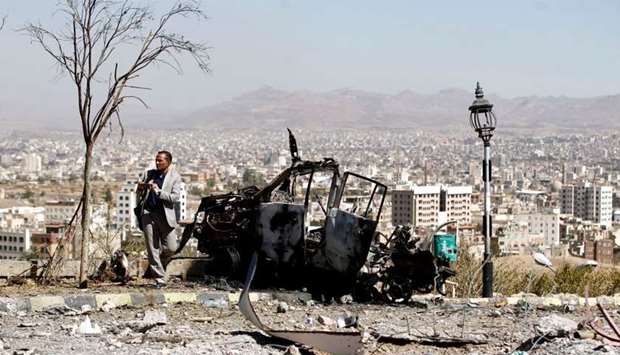 A Yemeni man takes a picture of the debris following an airstrike by the Saudi-led coalition