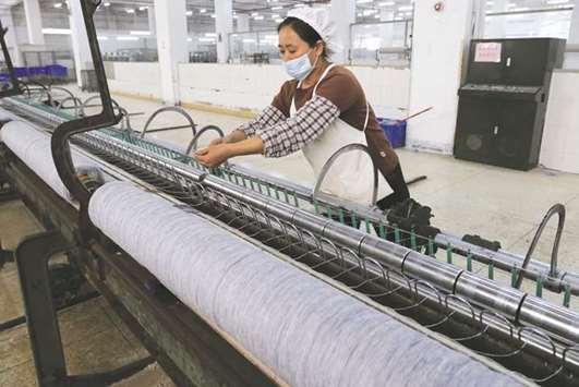 A worker disentangles wool yarn at a spinning machine at a factory in Zhuhai City, Guangdong province. Profits at Chinau2019s industrial firms rose 14.9% to 785.8bn yuan ($120.05bn) in November, the National Bureau of Statistics (NBS) said on its website yesterday.