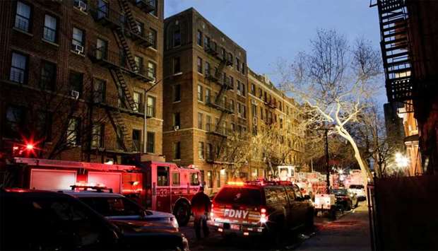 New York Police Department (NYPD) officers and Fire Department of New York (FDNY) personnel work on the scene of an apartment fire in Bronx