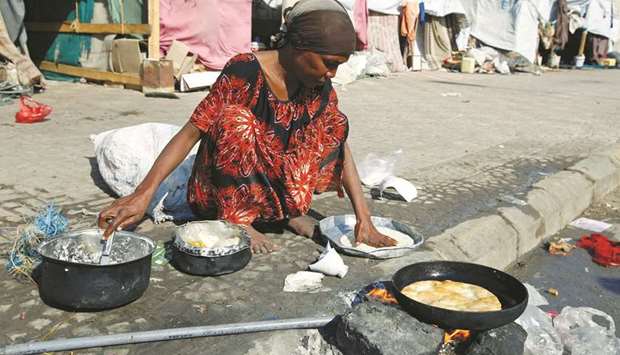 A woman displaced by the war in the northwestern areas of Yemen cooks outside her makeshift hut on a street in the Red Sea port city of Hodeida, Yemen December 25. Yemen is now bearing the brunt of two of the most devastating manmade crises: violent conflict and climate change.
