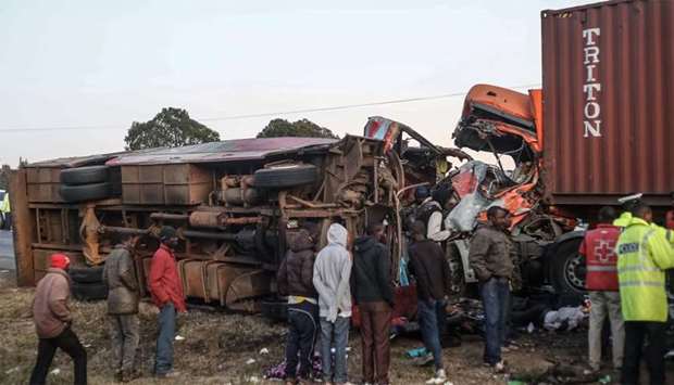 People look at the wreckage of a bus and a lorry that crashed in a head-on collision, killing thirty-six people