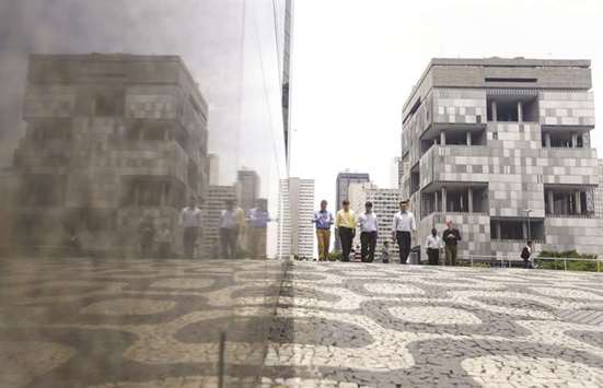 People walk next to the Petrobras headquarters (right) in Rio de Janeiro (file). Petrobras may be making progress in its plan to reduce debt, but a former shareholder in the state-controlled energy giant isnu2019t ready to jump back in quite yet.