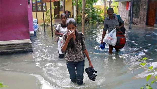 Residents carry their belongings as they evacuate their house after flooding caused by Cyclone Ockhi in the coastal village of Chellanam in Kerala, on Saturday.