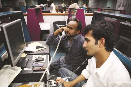 Traders monitor stocks in a trading hall at the Karachi Stock Exchange in Pakistan (file). Analysts are reckoning Pakistan Stock Exchange to grow around 20% in 2018 despite  getting hit by a negative benchmark index return of 15% to become the worst performing emerging market of 2017.