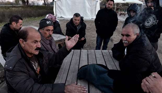 Yazidi refugees have a discussion as they sit outside at the Serres refugee camp, northern Greece, on November 24, 2017.