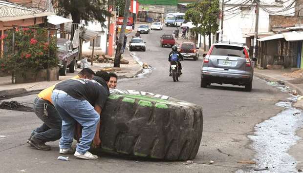 A group of men struggle to move a tractor wheel to clear a road where supporters of the presidential candidate Salvador Nasralla set up a barricade during protests in Tegucigalpa yesterday.