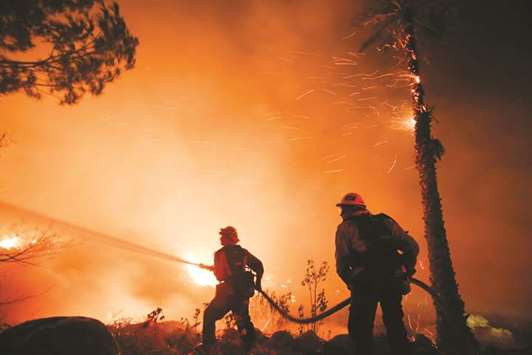 Firefighters battle a wildfire as it burns along a hillside near homes in Santa Paula, California.