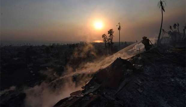 A firefighter hoses down flareups at the two-storey Hawaiian Village Apartment complex that burnt to the ground during the Thomas wildfire in Ventura, California.