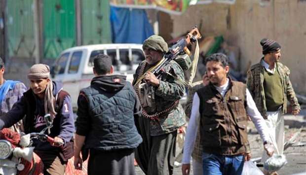 A Houthi rebel fighter slings a heavy machine gun on his shoulder as he walks down a street in Sanaa.