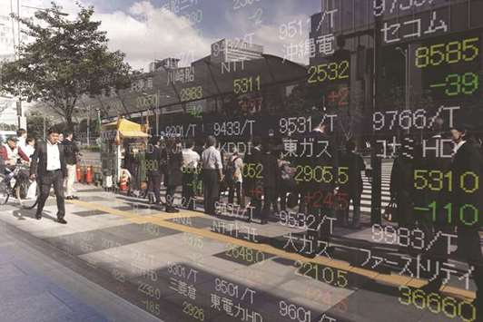 Pedestrians are reflected in an electronic stock board outside a securities firm in Tokyo. The benchmark index of Tokyo stocks ended 1.5% higher at 22,498.03 points yesterday.