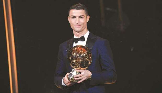 This handout photo released  yesterday by Lu2019Equipe shows Portugese player Cristiano  Ronaldo posing with the Ballon du2019Or France Football trophy in Paris. The Real Madrid forwardu2019s second successive win draws him level alongside Barcelona rival Lionel Messi on five Ballon du2019Ors, after beating the Argentinian and Brazilian Neymar to this yearu2019s award.