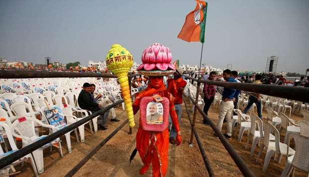 A supporter carries overhead a model of lotus, the election symbol of India's ruling Bharatiya Janata party (BJP), as he arrives to attend a campaign meeting addressed by Prime Minister Narendra Modi ahead of Gujarat state assembly election in Kalol on the outskirts of Ahmedabad, India.