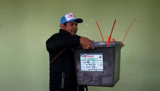 An official from the election commission carries a ballot box to count the votes, a day after the parliamentary and provincial elections in Kathmandu, Nepal.