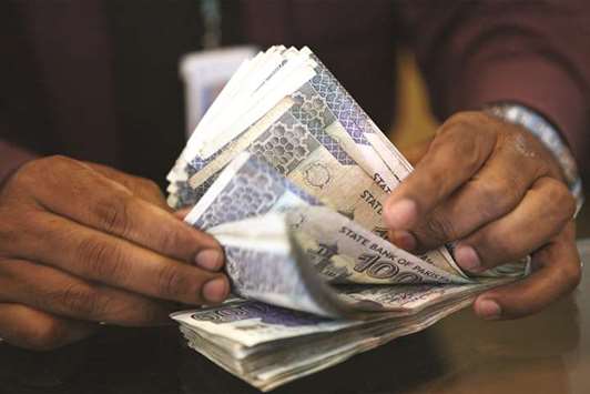 A Barclays Bank Pakistan employee counts rupee banknotes in one of the banku2019s branches in Karachi (file). The currency u2013 officially a managed float u2013 has been held steady at about 105 per dollar since July, when the central bank last let the rupee fall temporarily, causing a spat between the regulator and the finance ministry.