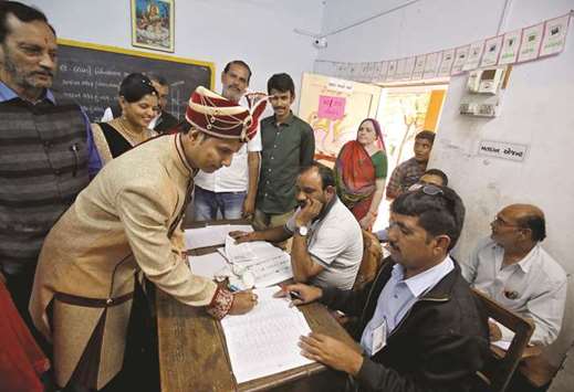 A groom signs a register before casting his vote at a polling booth during the first phase of assembly election in Limbdi town of Surendranagar district in Gujarat yesterday.