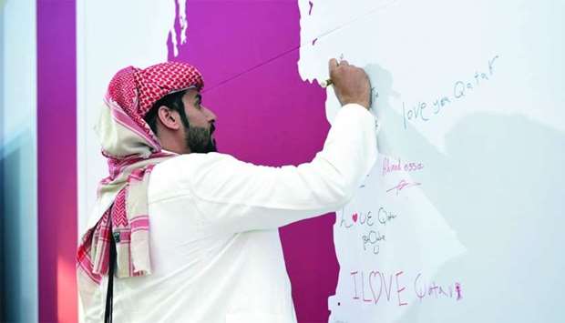 A visitor signs the pledge wall at Qatar Foundationu2019s tent in Darb Al Saai.rn