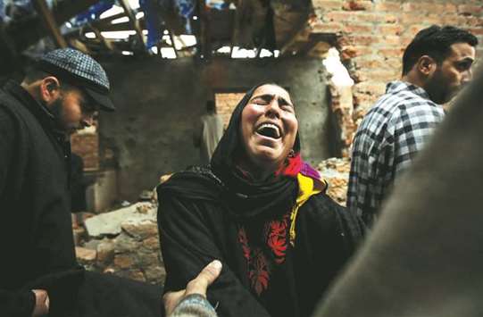 A woman cries inside her damaged house which was damaged in a gunbattle between security forces and suspected militants in Mujgund on the outskirts of Srinagar, yesterday.
