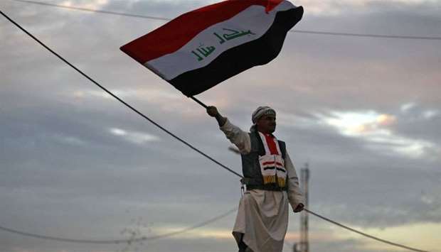 Iraqi man waves his national flag in Baghdad's Tahrir Square