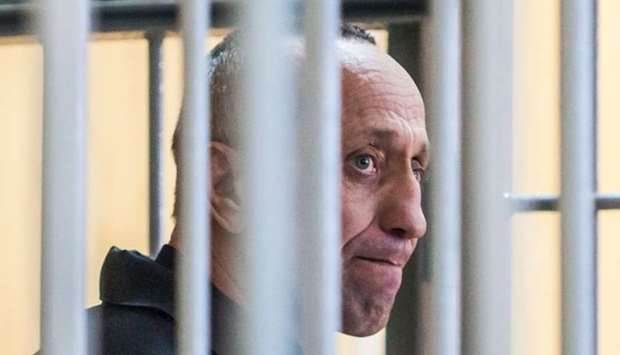 Mikhail Popkov stands inside a defendants' cage during a court hearing in Irkutsk