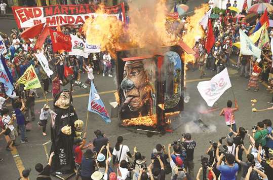Activists burn portraits of President Rodrigo Duterte during a rally to commemorate the 70th International Human Rights Day near the Presidential Palace in Manila, yesterday.