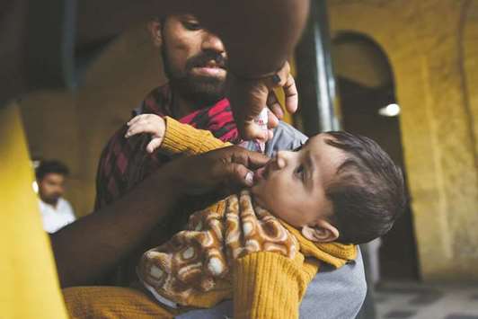 A health worker administers polio vaccine drops to a child during a vaccination campaign in Karachi.