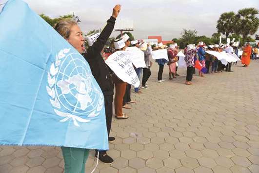 A Cambodian demonstrator, left, displays the UN flag as she shouts slogans during a rally marking International Human Rights Day in Phnom Penh yesterday.