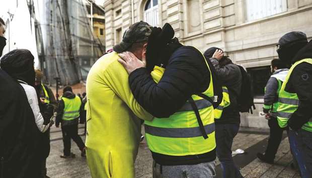 Protesters wearing yellow vests (Gilets jaunes) hug on the Champs Elysees in Paris on December 8, 2018 during a protest against rising costs of living they blame on high taxes. u201cThe protests by the gilets jaunes are proof that when people finally decide to stand up and say u2018enoughu2019, governments have no choice but to listenu201d.