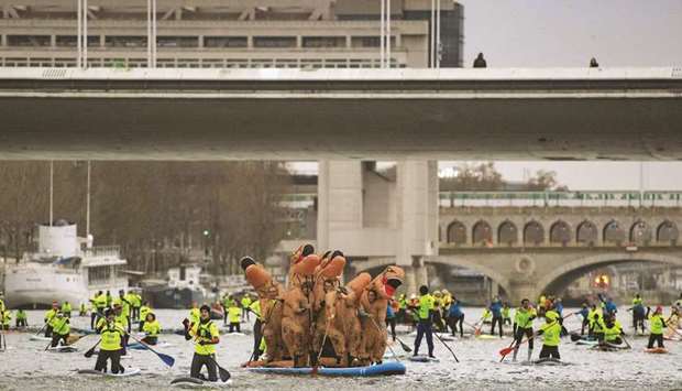People dressed as dinosaurs take part in the Nautic Paddle Race on the Seine river in Paris.