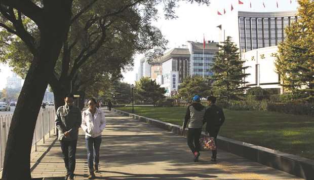 Pedestrians walk past the Peopleu2019s Bank of China headquarters (right) in Beijing. Chinese banks extended $182bn in net new yuan loans in November, slightly more than  analysts had expected and up from the previous month, according to data published by the central bank yesterday.