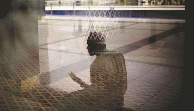 A man is reflected in a window as he prays outside the main prayer hall at the National Mosque of Malaysia in Kuala Lumpur (file).  Malaysiau2019s finance ministry has approved a plan to revive the  balance sheet of Lembaga Tabung Haji, a state fund tasked with helping Muslims save for a pilgrimage to Makkah.