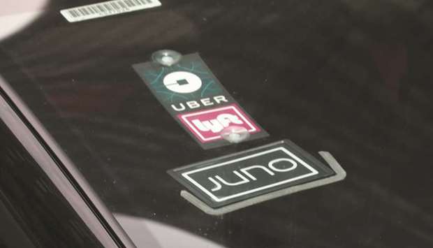 The Uber, Lyft and Juno logos are seen on a car in New York City. Uber and Lyft are driving side-by-side on the road to a stock market debut, and that may not bode well for Lyft as investors decide where to place their bets in the ride-hailing sector.