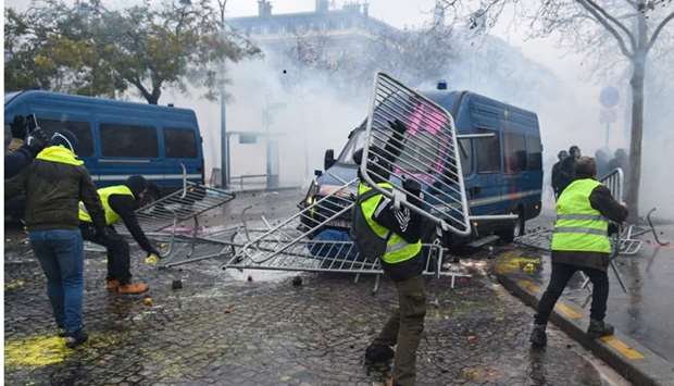 A demonstrator throws a metal barrier on a gendarmerie vehicle during a protest of Yellow vests (Gilets jaunes) against rising oil prices and living costs on the Champs Elysees in Paris