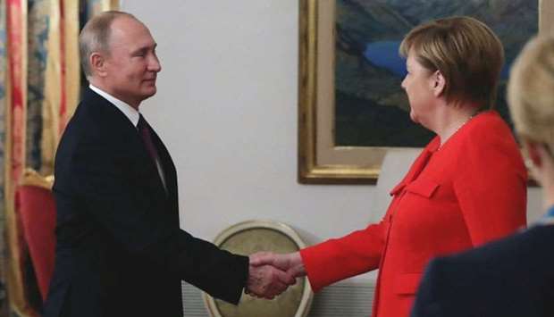 Russian President Vladimir Putin (L) shakes hands with German Chancellor Angela Merkel